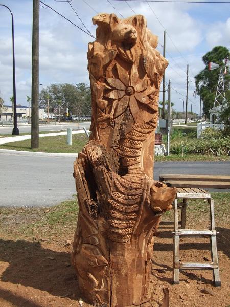 totem chainsaw sculpture with wolf , eagle and hummingbirds